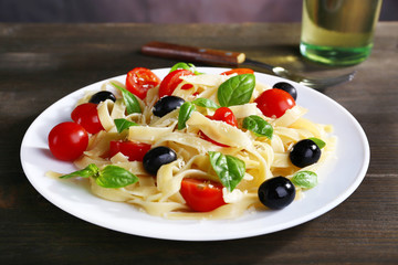 Spaghetti with tomatoes, olives and basil leaves