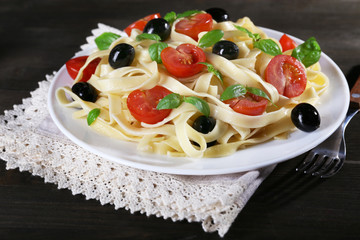 Spaghetti with tomatoes, olives and basil leaves