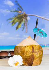 Kokosnuss am Strand mit Strohhalm und Schirmchen