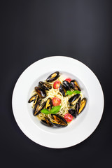 White plate of italian pasta with mussels, cherry tomato  and he