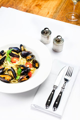 White plate of italian pasta with mussels, cherry tomato  and he