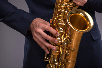 Fototapeta premium Close-up picture of a trumpet in hands of a jazz man in a suit i