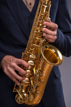 Close-up picture of a trumpet in hands of a jazz man in a suit i
