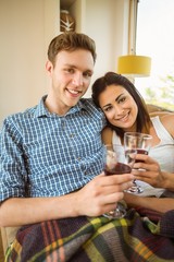 Happy young couple relaxing on the couch with red wine
