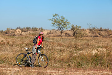 Woman standing next to a mountain bike and looking at the camera