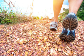 young fitness woman hiker legs walking on seaside mountain trail