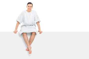 Cheerful male patient sitting on a blank panel