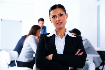 Businesswoman with arms folded standing in front of a metting