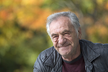 handsome old italian man in a park at fall