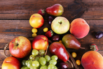 Different berries and fruits on tray on wooden table close-up