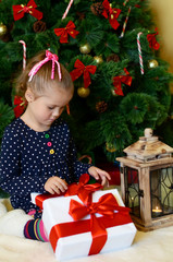 The little girl at a Christmas fur-tree with gifts