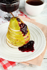 Tasty dessert with sliced pear, cream and berry sauce