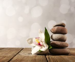 Spa stones and white orchid on wooden table on light background