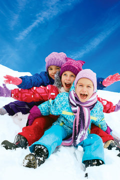 Winter fun, snow, happy children sledding at winter time