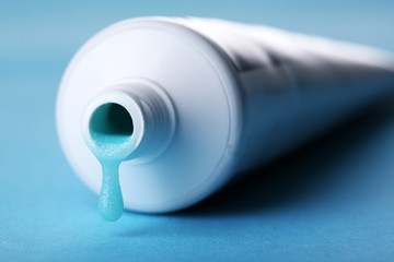 Tube with blue toothpaste on color background