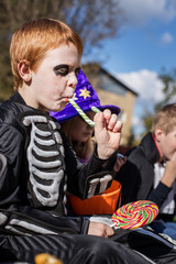 Red haired child with Halloween costume eating colorful candy