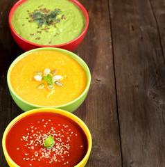 Three fresh soups on a wooden table