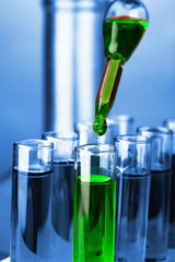 Laboratory pipette with drop of color liquid over glass test