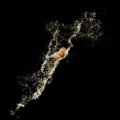 Champagne splashes with cork on black background