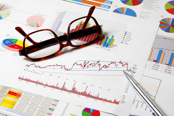 Glasses and pen on business finance chart