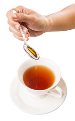 Female hand mixing honey with tea over white background