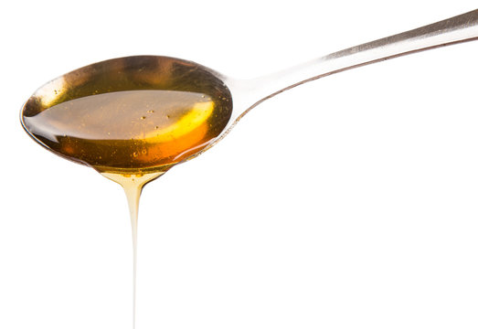 A spoon of honey over white background