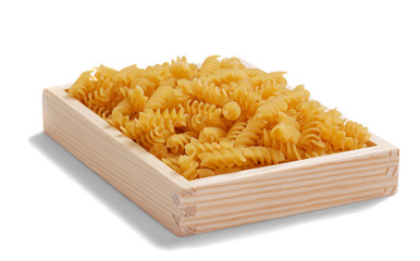Wooden box with uncooked Italian spiral pasta - Rotini. On white