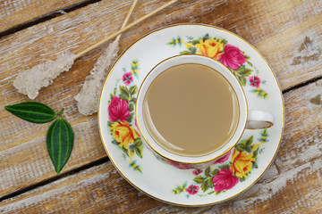 Milk tea in vintage cup, sugar stick on wooden surface