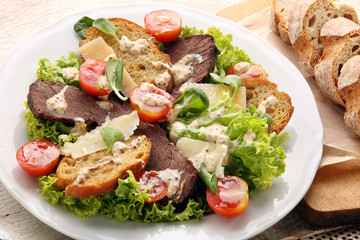 Salad with slices of roast beef with truffle sauce and toasts