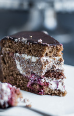 eating chocolate cake with cream and cherry on white plate