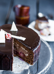section of chocolate cake with cream and cherry on the stand