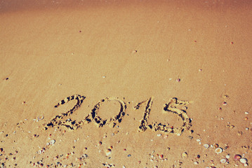 Fototapeta premium New year 2015 written on sandy beach. retro filtered image