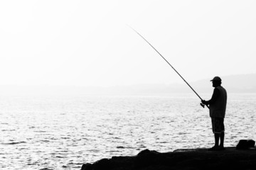 Evening fishing. Lone fisherman fishing from the shore.