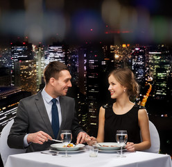 smiling couple eating main course at restaurant