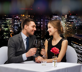 young couple with glasses of wine at restaurant
