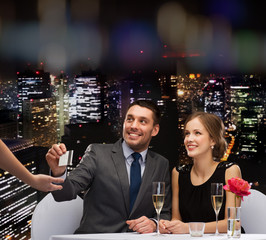 smiling couple paying for dinner with credit card