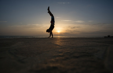 silhouetted man doing handstand in sunset
