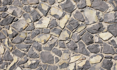Wall of black volcanic rocks closeup