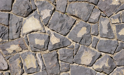 Wall of black volcanic rocks closeup