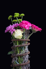Bouquet of flowers in metal spring isolated on black background