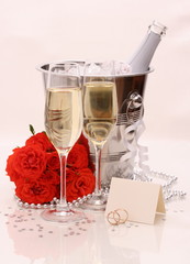 Two champagne glasses, red roses. golden wedding rings