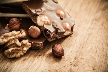 Milk chocolate and hazelnuts on wooden table