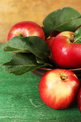 Ripe apples in bowl on wooden background