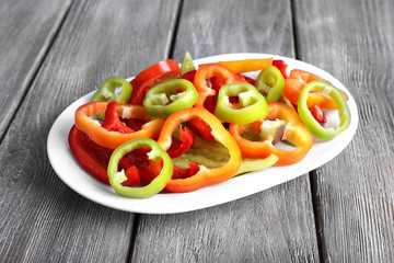 Sliced pepper on oval plate on wooden background