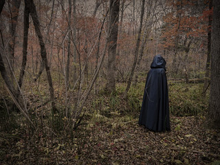 Obraz premium Scary figure in black mantle in the forest, desaturated