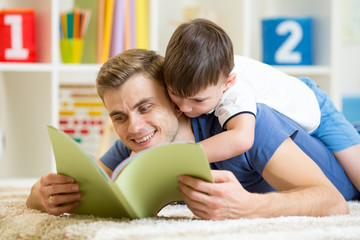father and his son read a book on floor at home