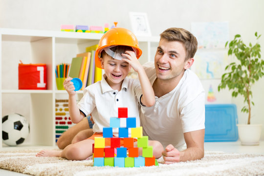 child and his dad play with building blocks