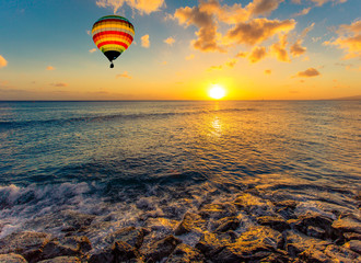 Naklejka premium Hot air balloon over the sea at sunset