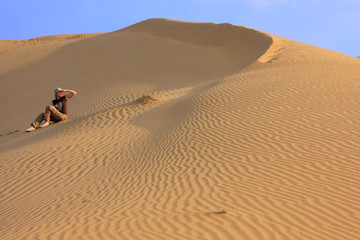 Fototapeta na wymiar Young woman sitting on dunes, Thar desert, Jaisalmer, India