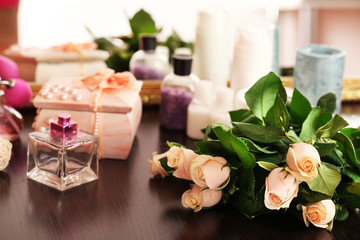 Obraz na płótnie Canvas Beautiful roses, perfumes on table near mirror